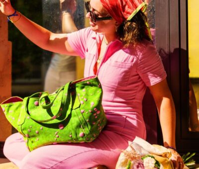 Femme en tenue rose avec sac à main SoWoit Sasha Tote Bag Impulsion vert, esprit “Emily in Paris”, lumière ensoleillée